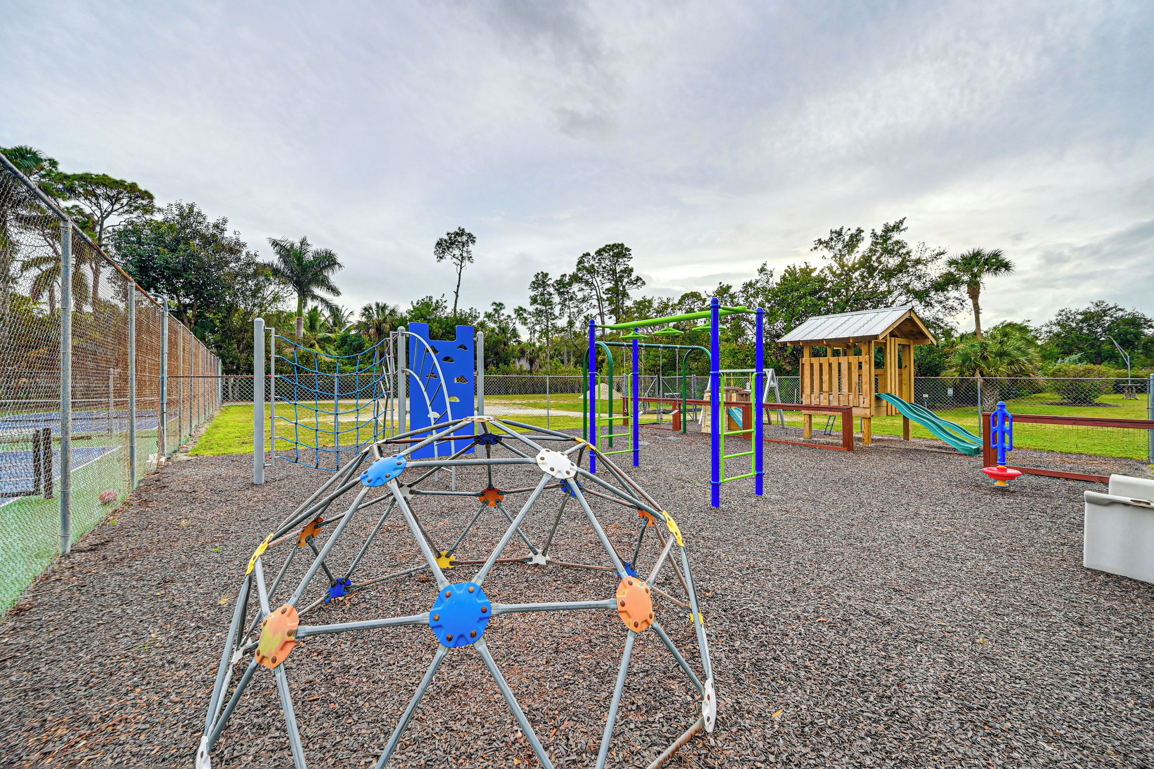 A playground with a climbing structure, slides, and a small wooden building.