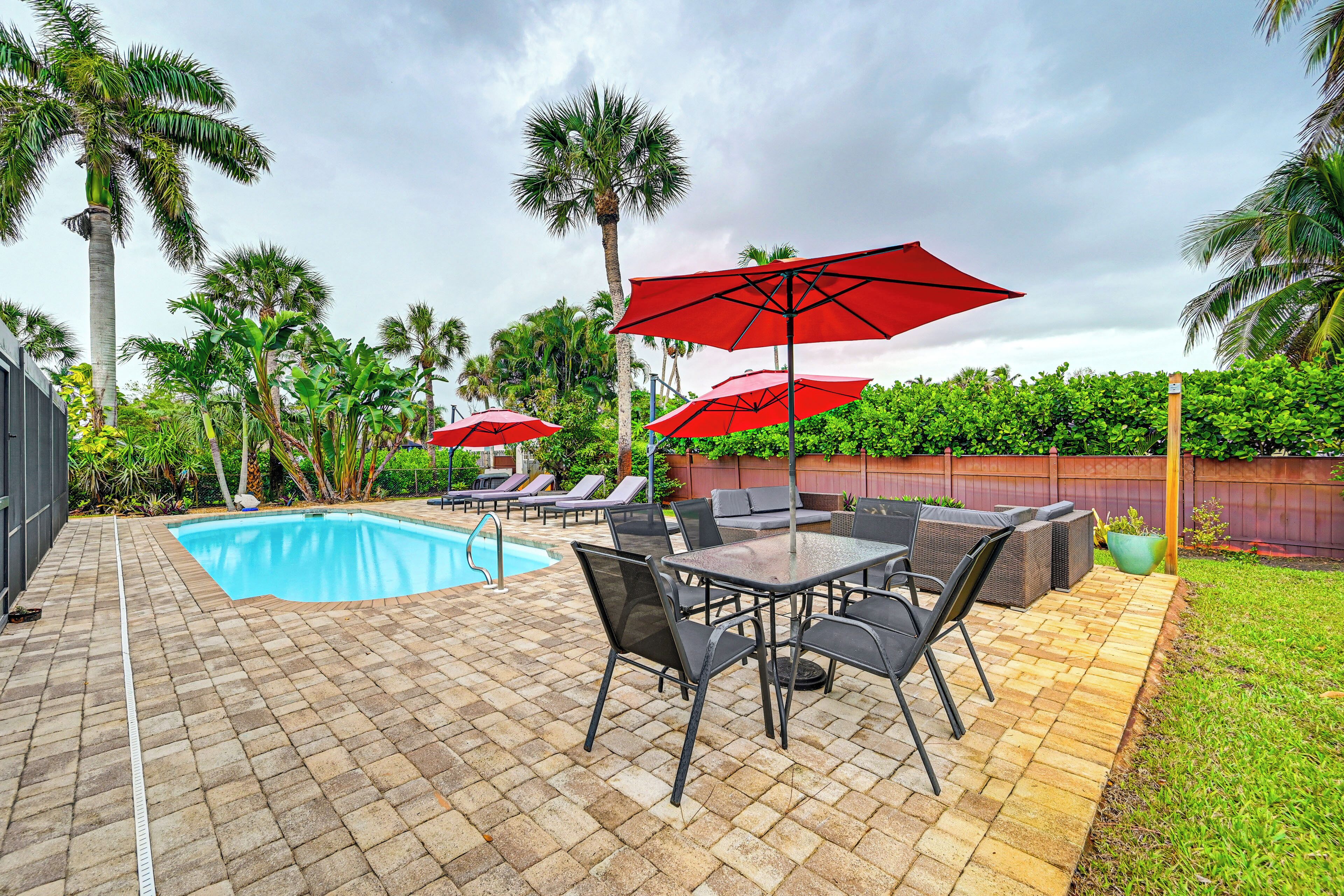 A backyard with a swimming pool, patio furniture, and umbrellas.