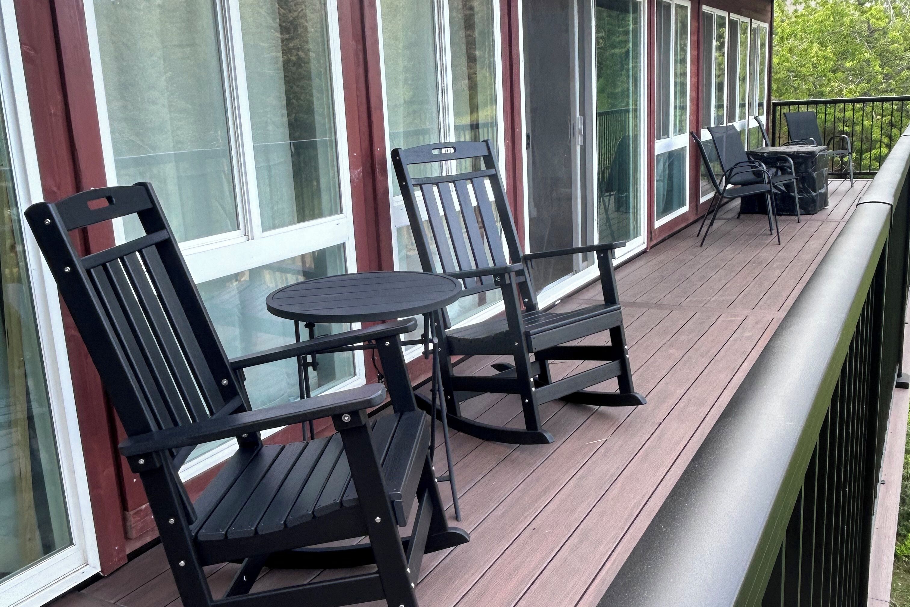 A covered outdoor area with a table and chairs, large windows, and a railing.