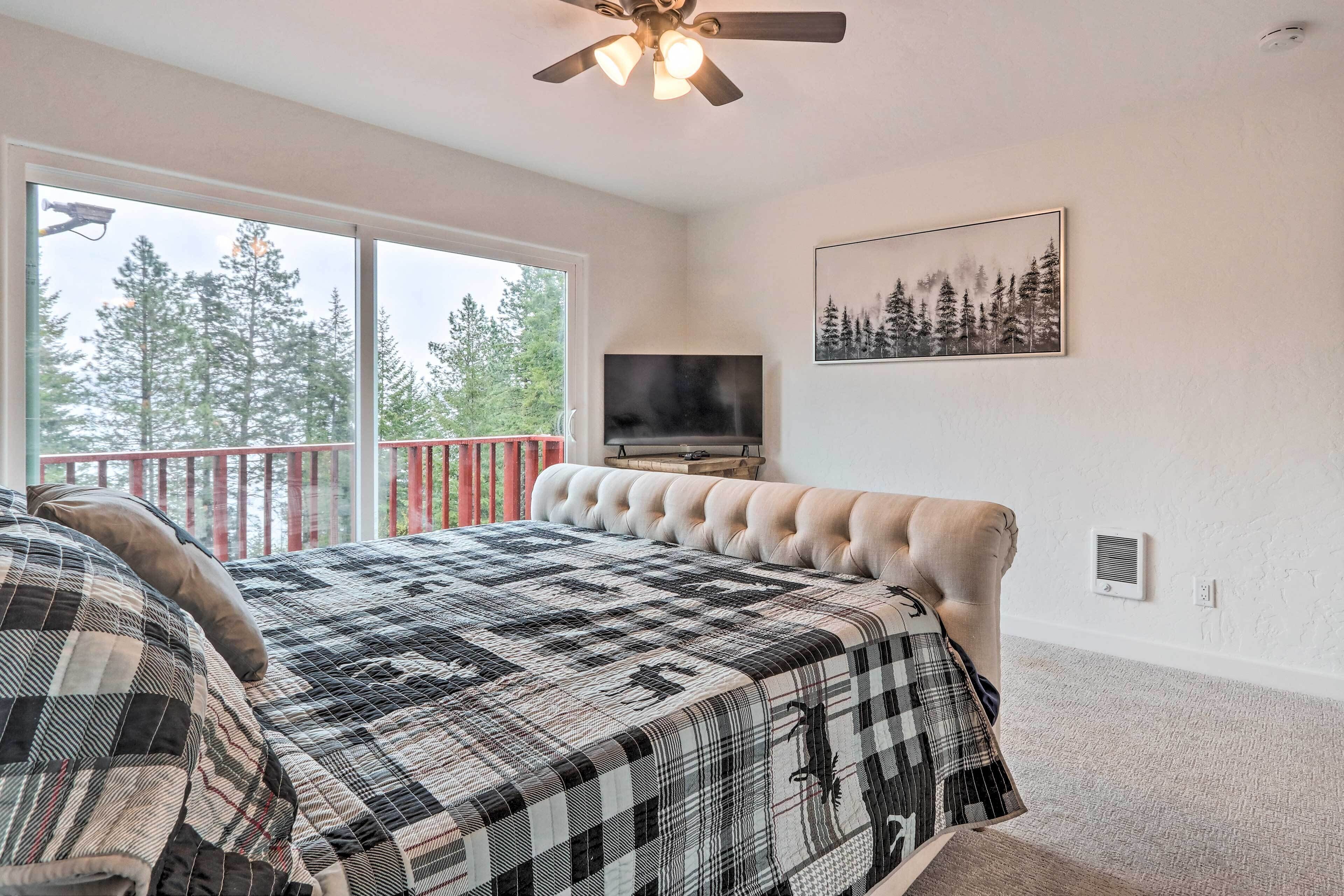 A bedroom with a large bed, a TV, a ceiling fan, and a balcony with a red railing.
