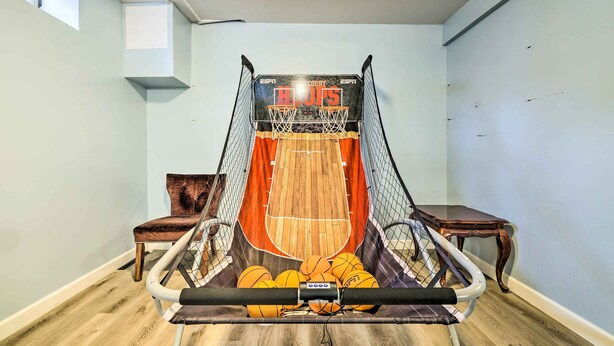A basketball court with a net, wooden flooring, and a chair. - Hot Tub, Game Room: Peaceful Poconos Home! (Long Pond)
