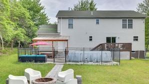 A backyard with a swimming pool, a covered patio area, and a fire pit. - Hot Tub, Game Room: Peaceful Poconos Home! (Long Pond)