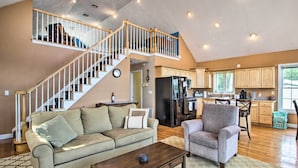 A spacious living area with a high ceiling, a staircase leading to an upper level, a kitchen with wooden cabinets, and a dining area. - Waterside Haven on Milton Pond w/ Deck & Boat Dock (Milton)