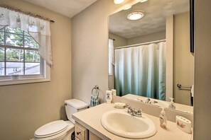 A bathroom with a toilet, sink, and mirror.