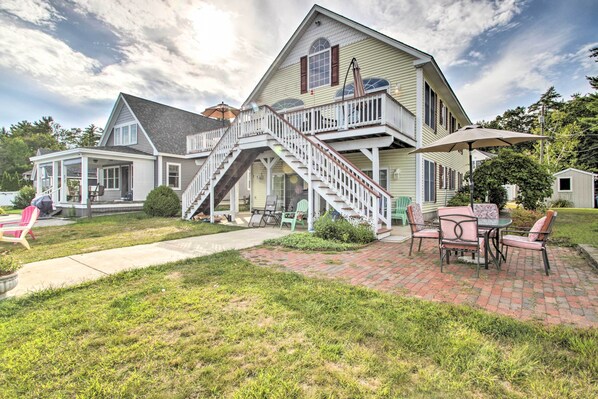 A two-story house with a covered patio, a staircase, and outdoor furniture.