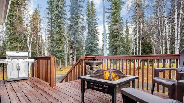 An outdoor deck with a grill and a fire pit, surrounded by a forest. - Peaceful Nature Escape w/ Deck in North Pole! (North Pole)