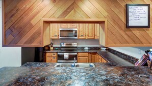 A kitchen with wooden cabinetry, a granite countertop, stainless steel appliances, and a sign with WiFi details. - Peaceful Nature Escape w/ Deck in North Pole! (North Pole)