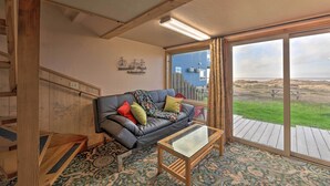 Una habitación con un sofá de cuero negro, una mesa de centro de vidrio y un ventanal con vista a la playa.