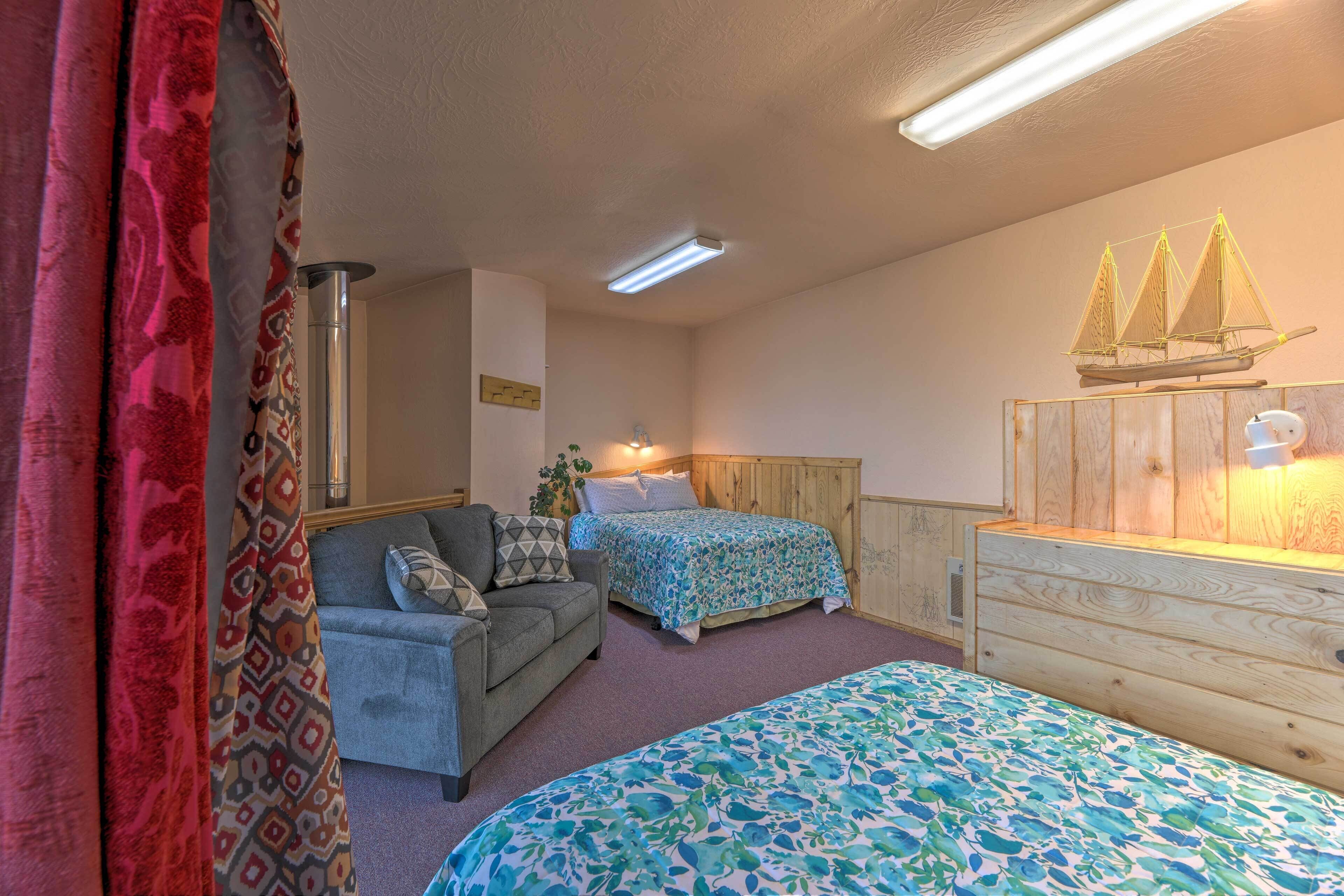 Une chambre avec deux lits, une commode en bois, une table de chevet, une lampe et une étagère murale sur laquelle est posé un modèle de bateau.
