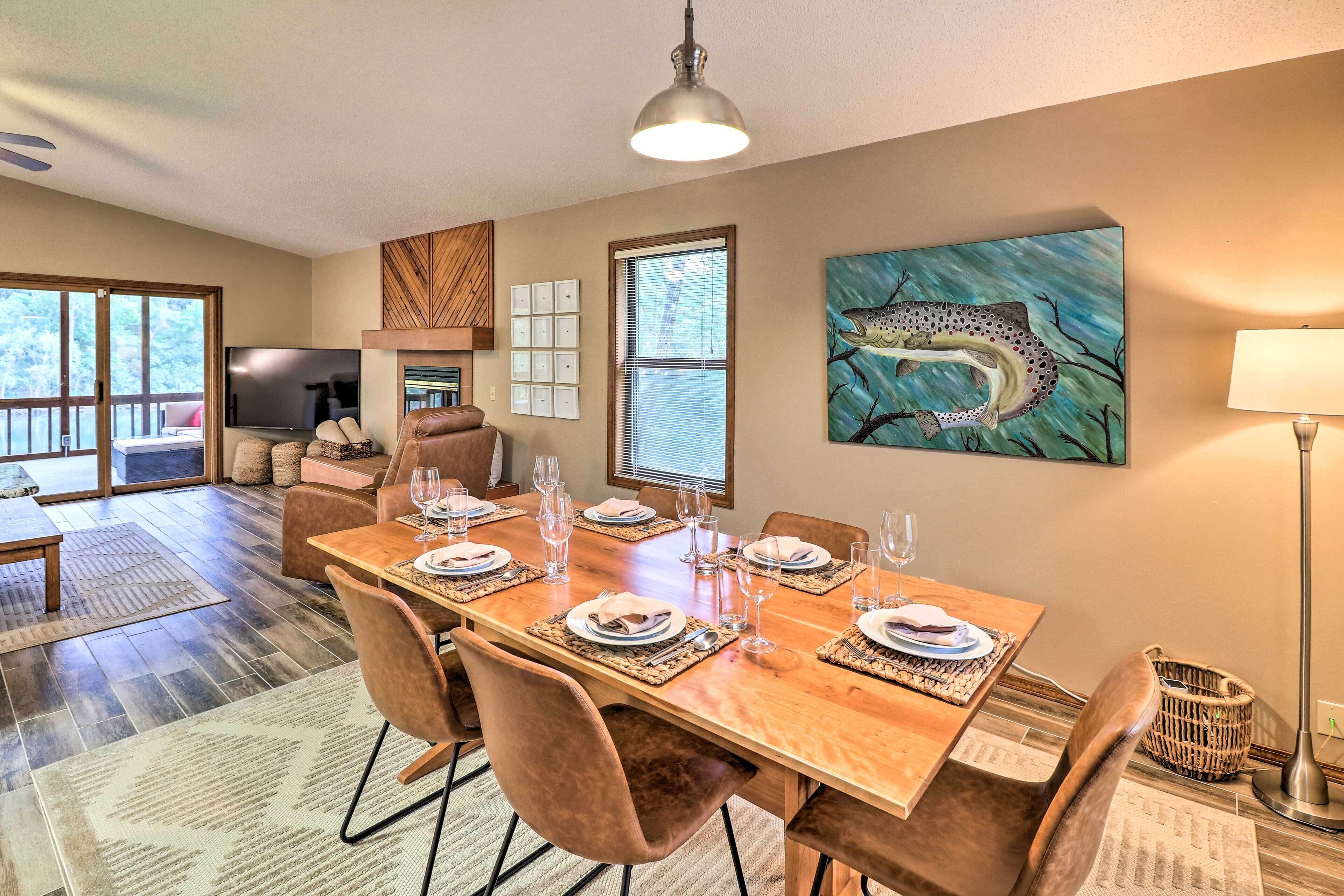 A dining area with a wooden table set for six, surrounded by chairs.