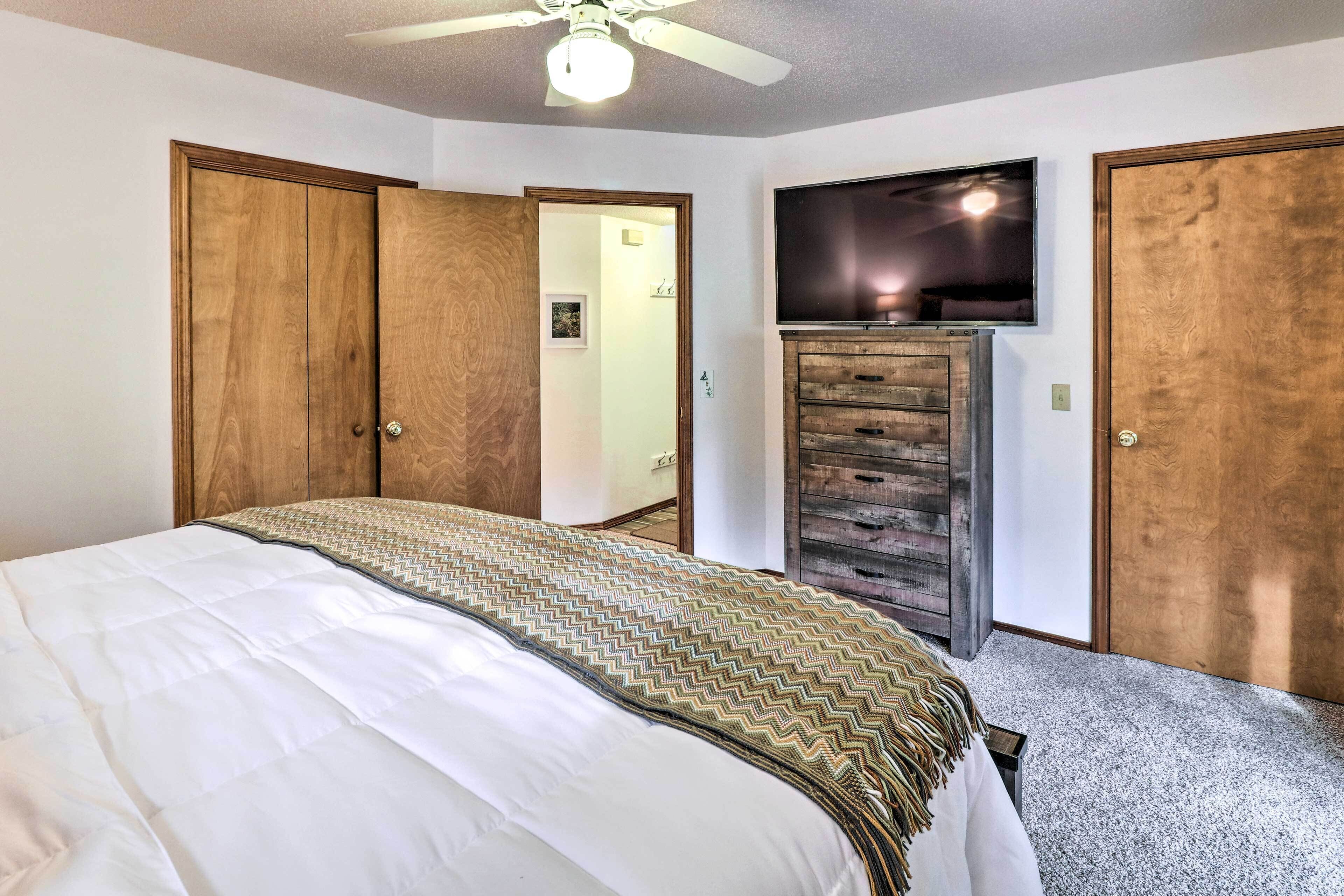 A bedroom with a bed, wooden wardrobe, and a TV mounted on the wall.