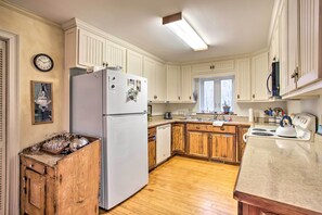 A kitchen with wooden cabinets, a white refrigerator, a wooden stove, and a window with blinds. - Blue Ridge Mountain Escape ~ 8 Mi to Chimney Rock (Gerton)
