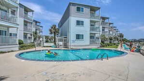 A multi-story building with balconies, a pool area with a diving board, and palm trees. - North Myrtle Beach Condo w/ Stunning Ocean Views! (North Myrtle Beach)