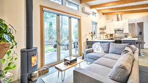 Ein modernes Wohnzimmer mit Kamin, einer Couch und einem Essbereich, im Hintergrund befindet sich eine Küche.