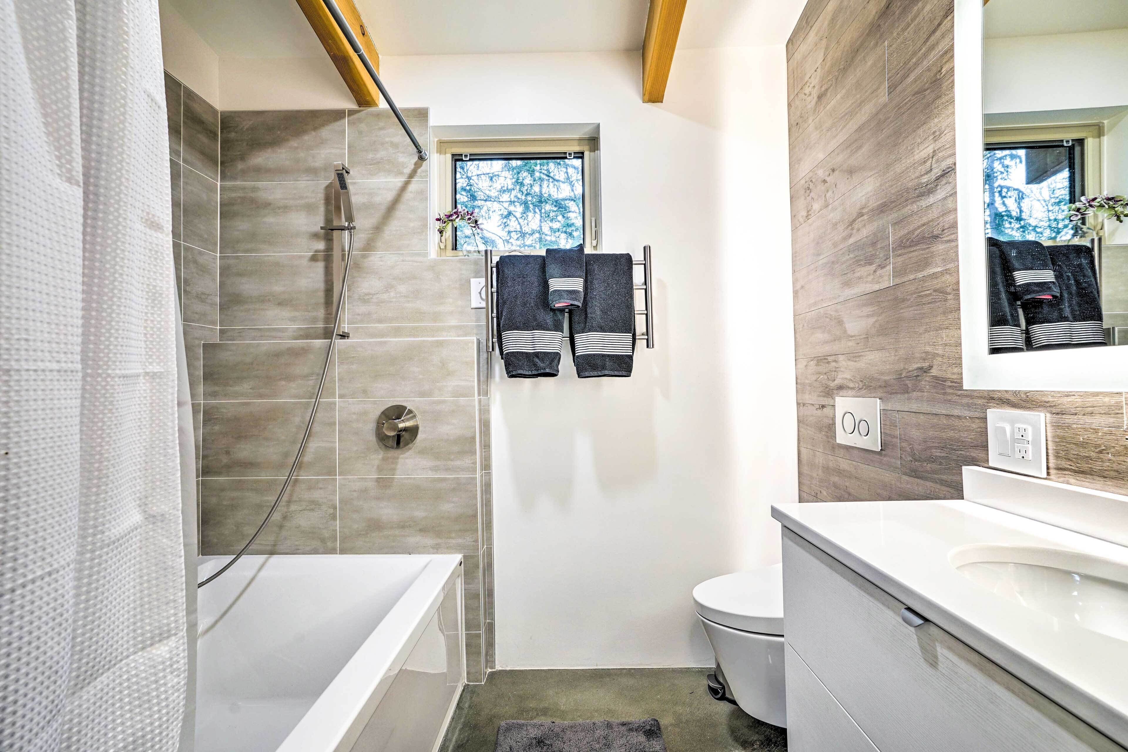 Een moderne badkamer met douche, toilet en wastafel.