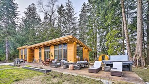 Eine moderne Blockhütte mit einer Terrasse, Sitzgelegenheiten im Freien und einer Grillzone.