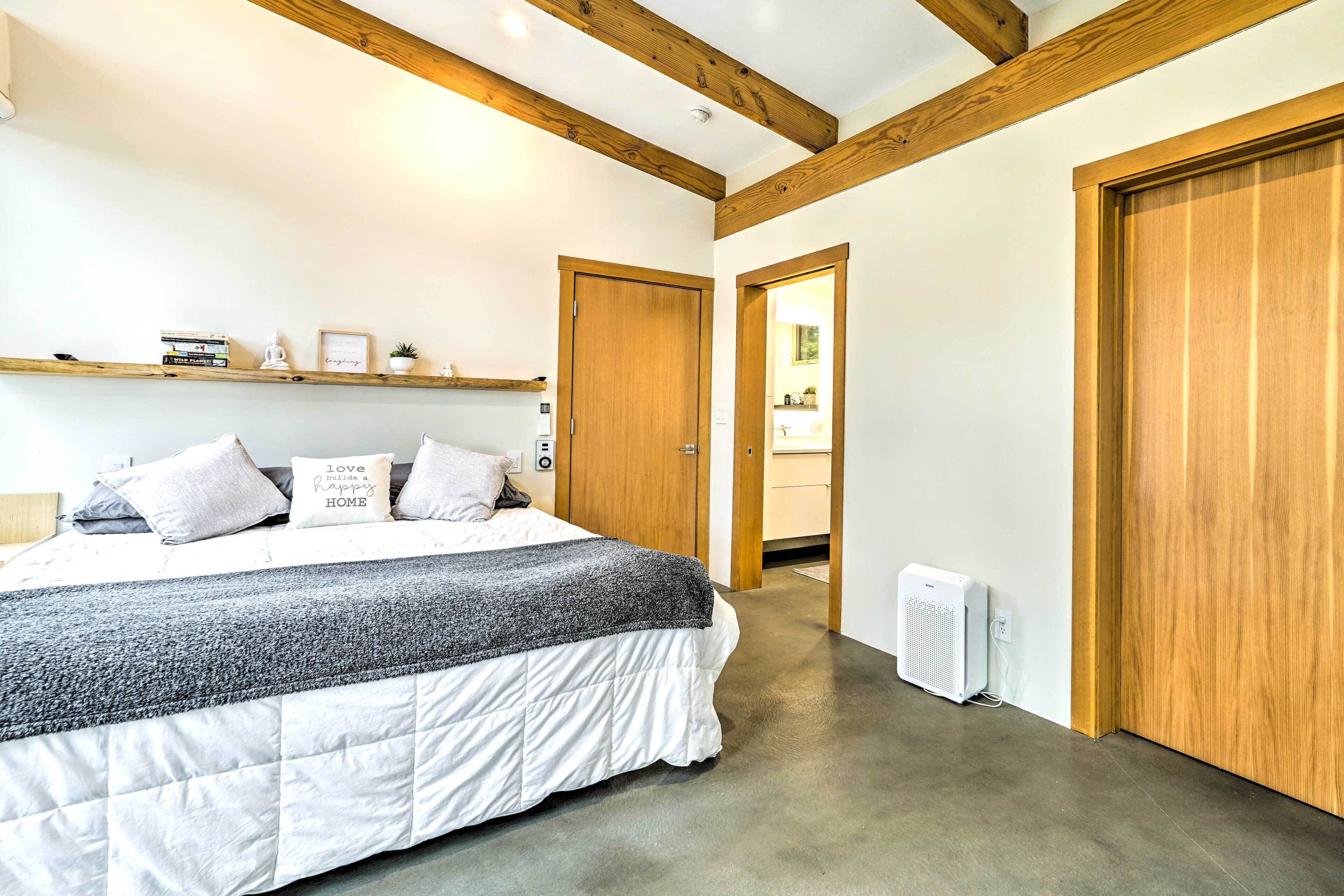 Une chambre à coucher avec un lit, une étagère remplie de livres et une statue de Bouddha, une porte et un radiateur.