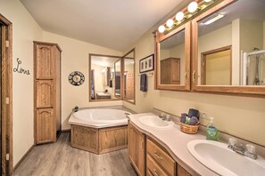 A bathroom with two sinks, wooden cabinets, a large mirror, and a vanity with a vanity lamp. - Tranquil Cabin Getaway Near Red Cedar Lake! (Birchwood)