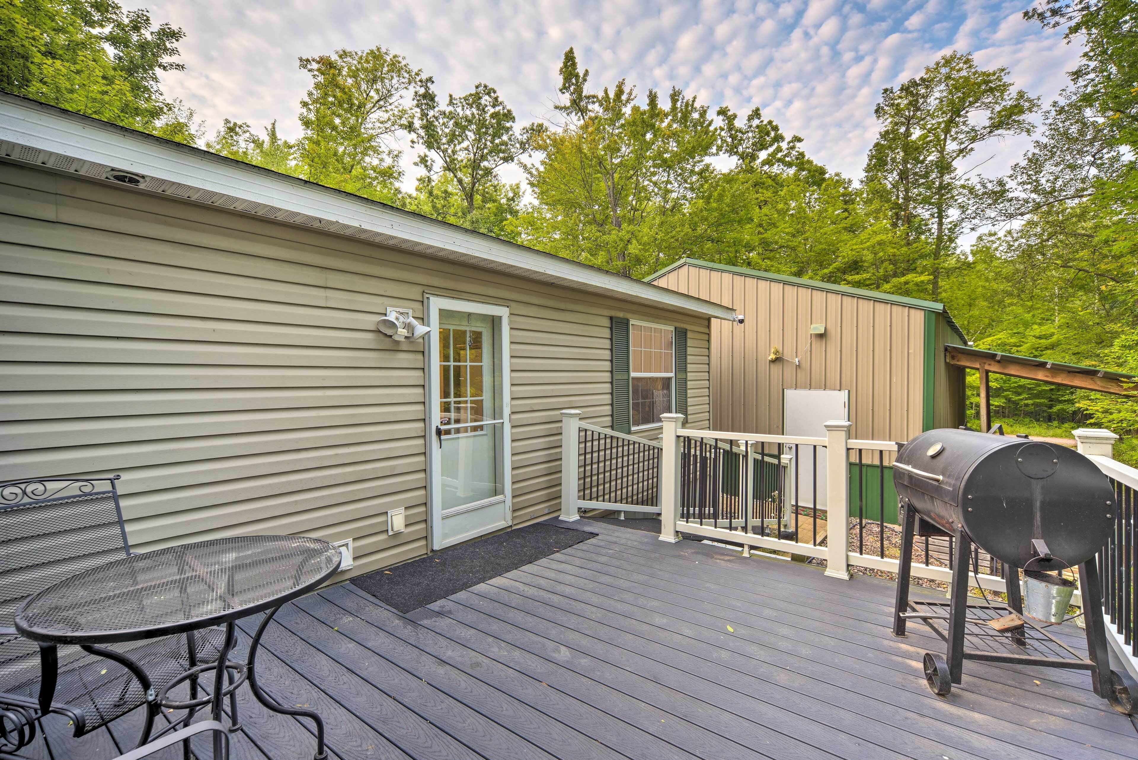 A deck with a grill, a table, and a door to a house.