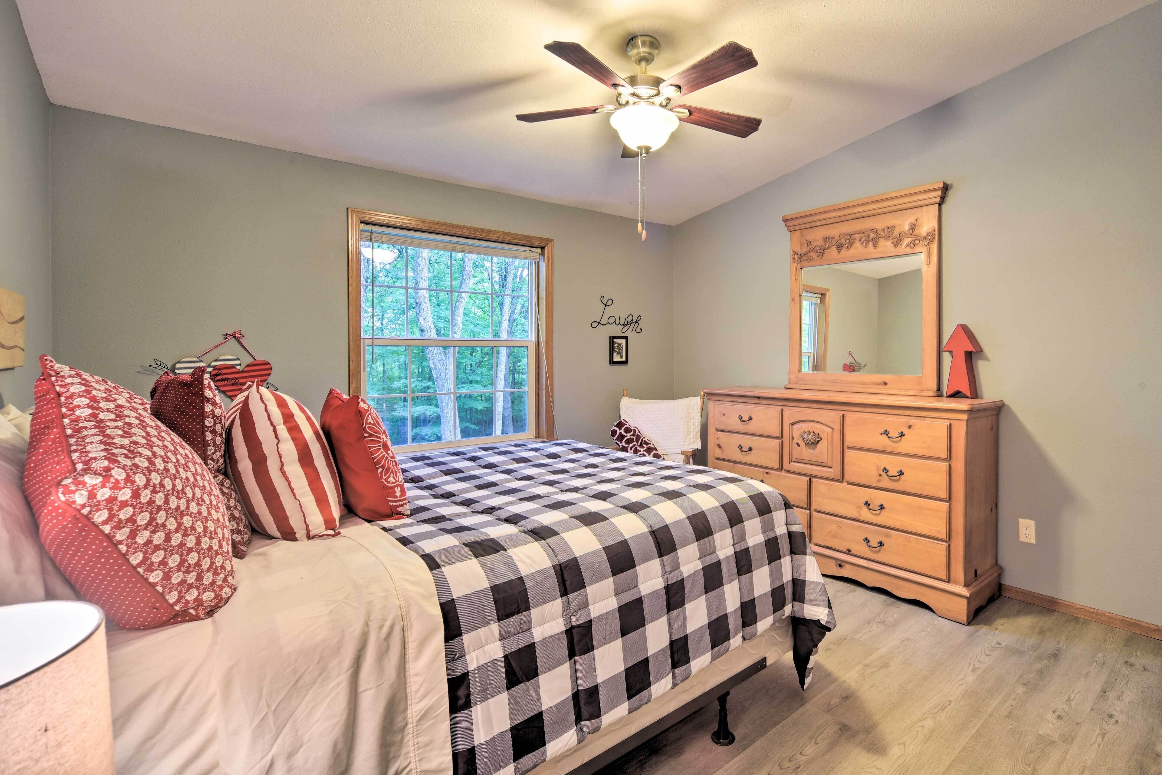 A bedroom with a bed, dresser, and ceiling fan.