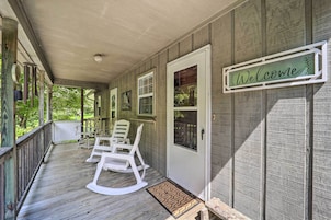 A wooden porch with rocking chairs and a welcome sign.