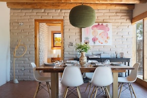 A dining area with a brick wall, a wooden ceiling, and a table set for four.