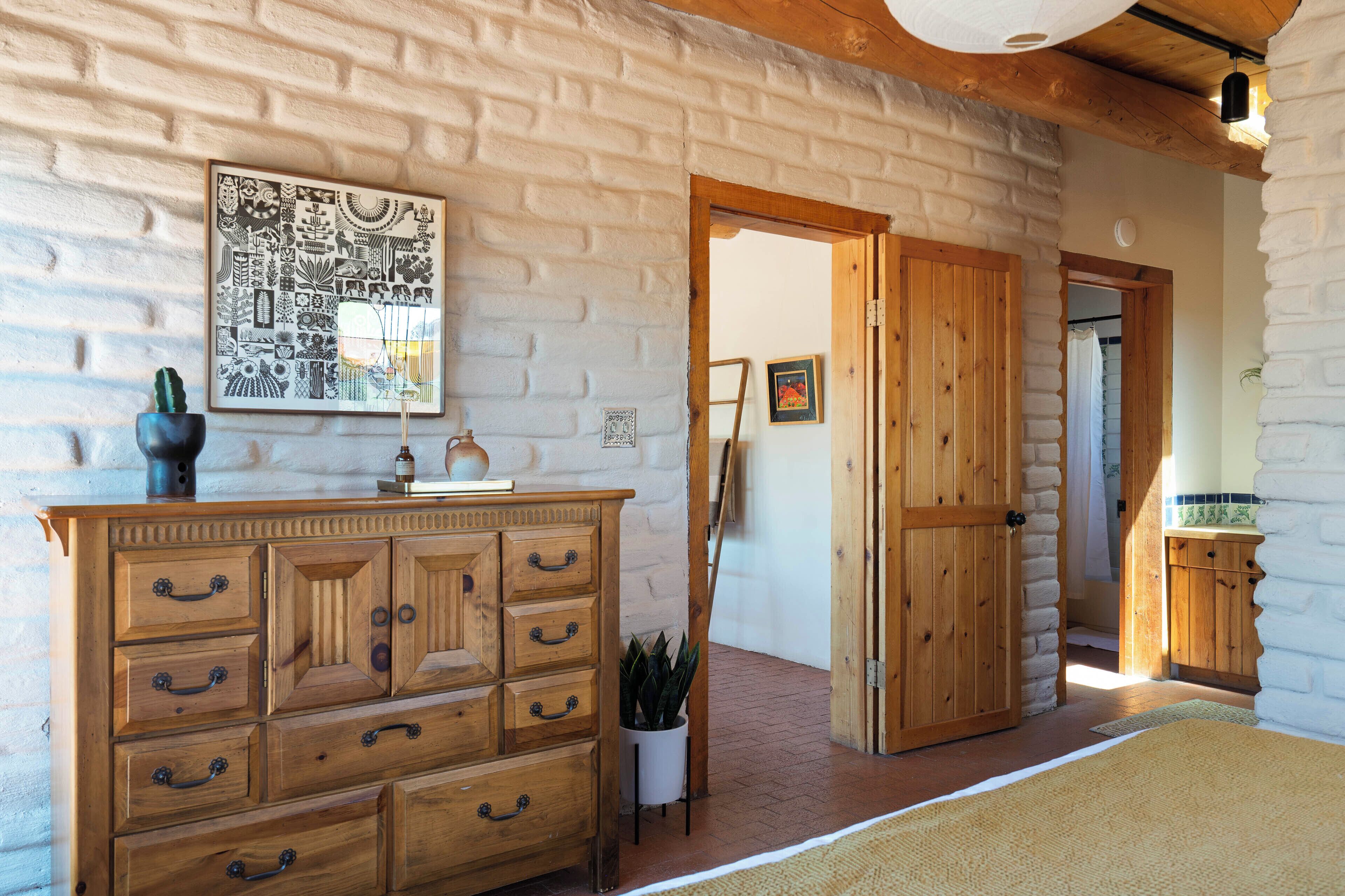 A room with a wooden dresser, a wall-mounted artwork, and a door leading to another room.