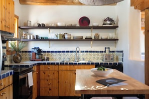 A kitchen with wooden cabinets, a tiled backsplash, a coffee machine, and a bowl of fruit on the counter.