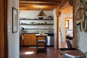 A kitchen with wooden cabinets, a stainless steel sink, and a hanging light fixture.