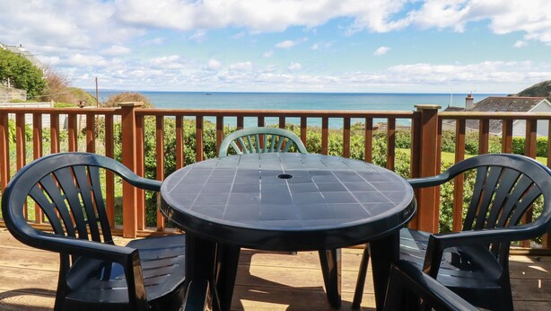 A round table with two chairs on a wooden deck overlooking the sea. - Beachcliff (St Austell)