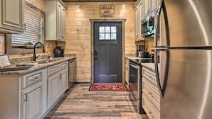 A modern kitchen with wooden cabinetry, a stainless steel refrigerator, and a welcome mat. - Hot Tub, Game Room, Decks: Cabin in Gatlinburg (Gatlinburg)