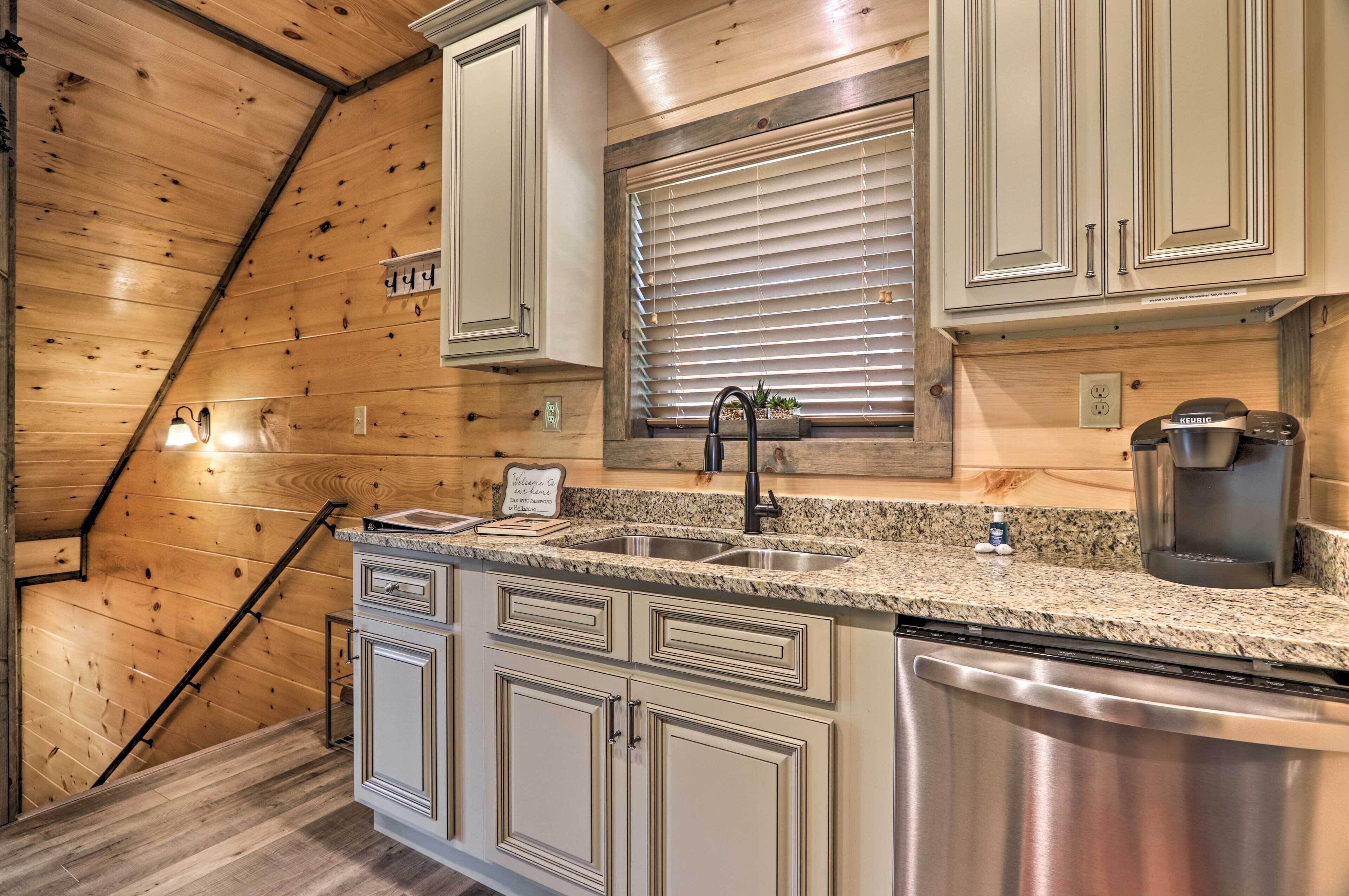 A kitchen with wooden walls, a granite countertop, stainless steel appliances, and a window with blinds.