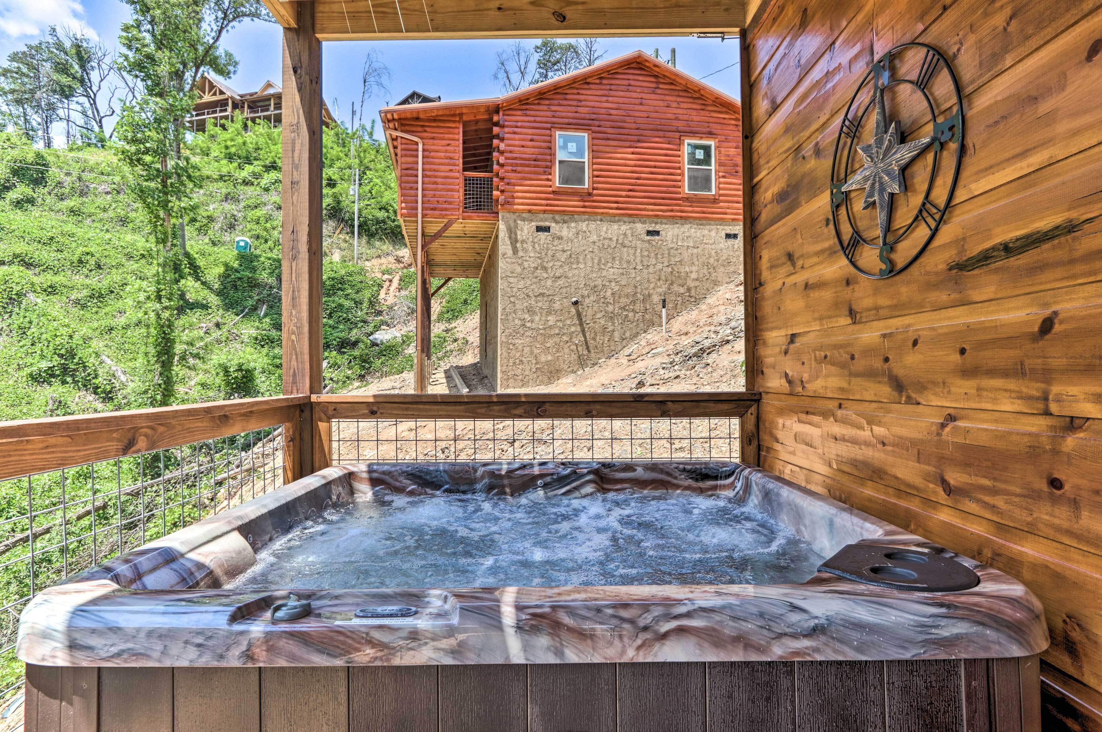 A hot tub with a wooden deck and a view of a red cabin in the background.