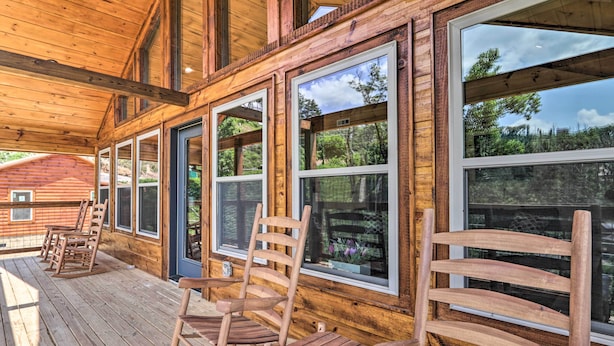 A wooden deck with rocking chairs and large windows overlooking a forested area. - Hot Tub, Game Room, Decks: Cabin in Gatlinburg (Gatlinburg)