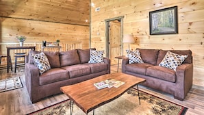 A cozy cabin interior with two brown sofas, a wooden coffee table, and a framed picture of a forest on the wall. - Hot Tub, Game Room, Decks: Cabin in Gatlinburg (Gatlinburg)