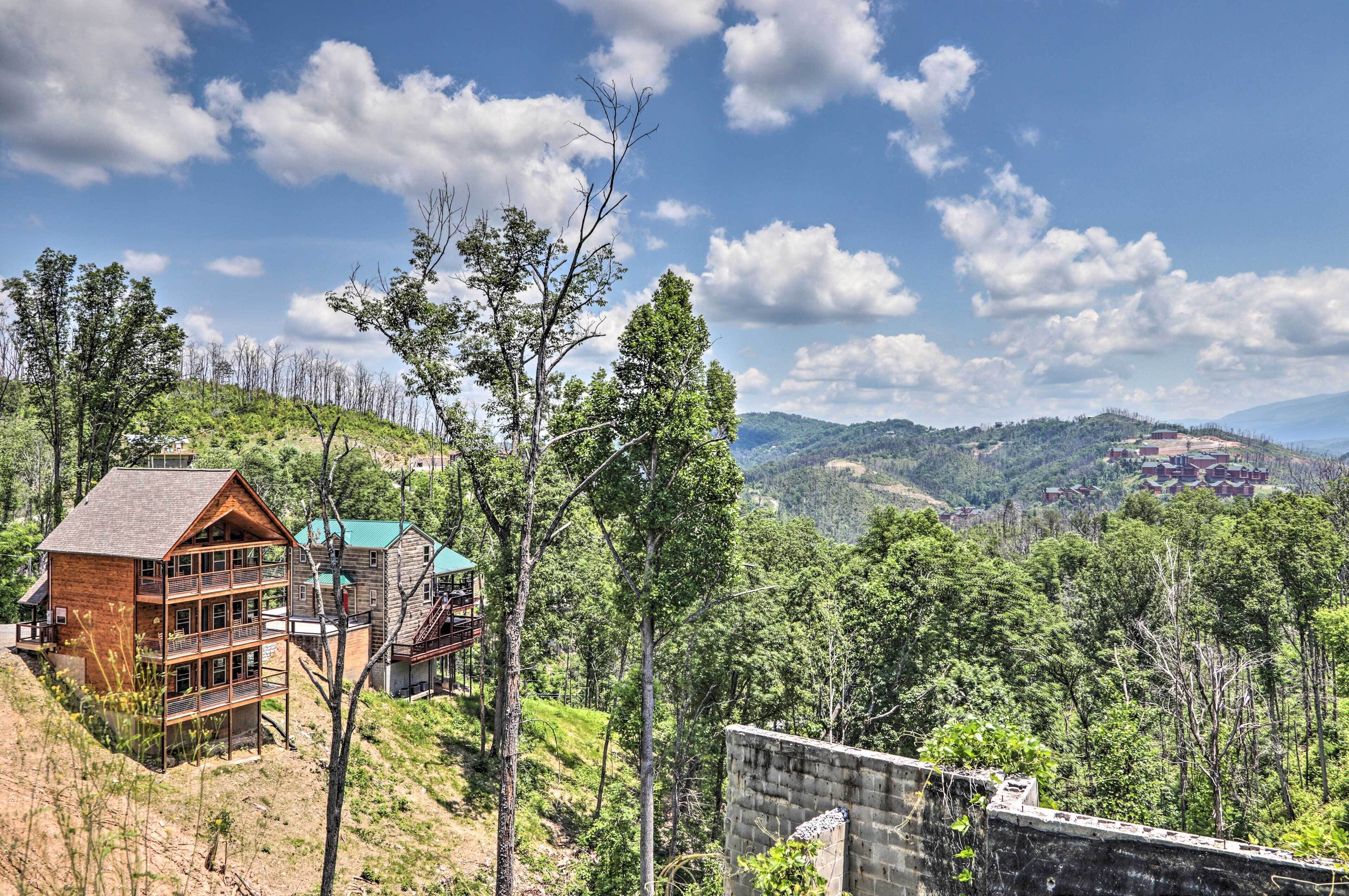 A multi-story wooden cabin with balconies, surrounded by a forested hillside.