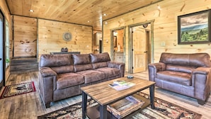 A wooden cabin interior with two leather sofas, a wooden coffee table, and a ceiling fan. - Hot Tub, Game Room, Decks: Cabin in Gatlinburg (Gatlinburg)