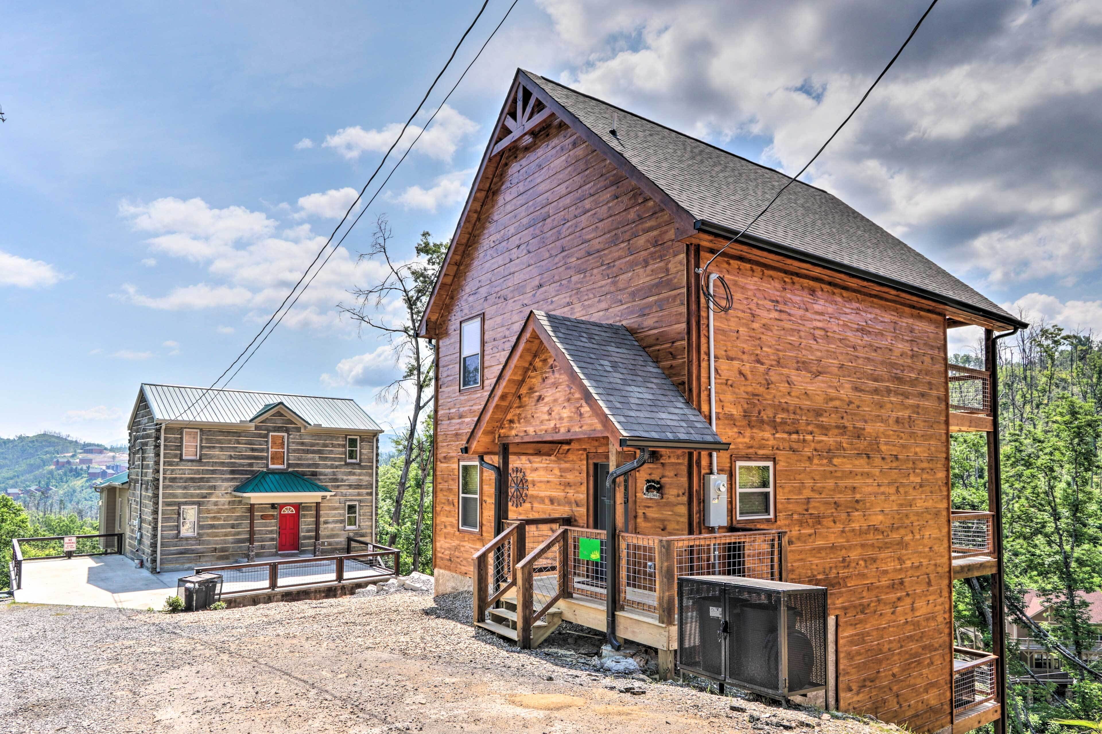 A rustic wooden cabin with a red door, a small porch, and a staircase leading to a balcony.