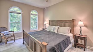 Une chambre à coucher avec un lit, deux lampes de chevet, une chaise et un ventilateur de plafond.