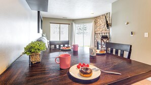 A dining area with a wooden table, a potted plant, and a plate with a donut and raspberries.