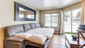 A bedroom with a large bed, a sofa, a TV, and a sliding glass door to a balcony.