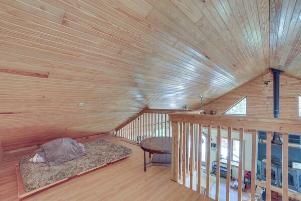 A wooden interior with a loft bed, a table, and a view of the outside. - Paradise Cottage: Trail Access Nearby (Paradise)