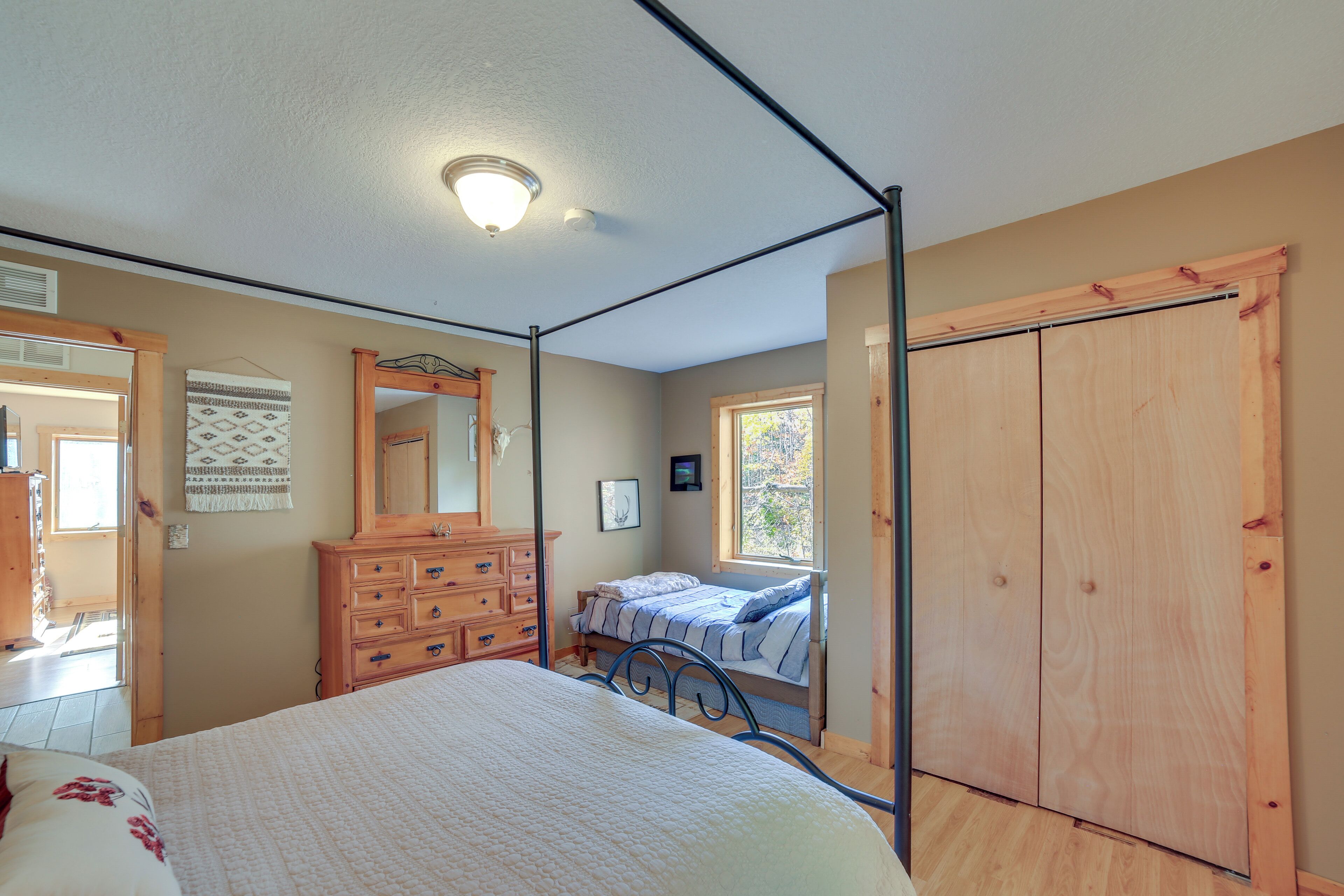 Un dormitorio con una cama con dosel, cómoda de madera y un armario grande.