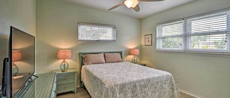 A bedroom with a bed, a ceiling fan, a dresser, a TV, and two bedside lamps.
