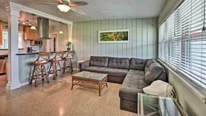 Ein Wohnzimmer mit einer Couch, einem Glastisch und einem Deckenventilator.
