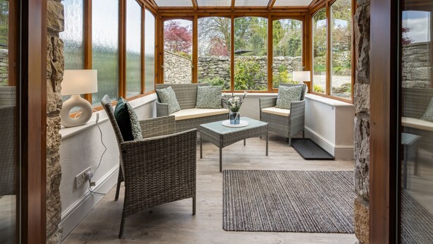 A sunroom with wicker furniture, stone walls, and large windows. - Manor Farm Barn Cottage - Close Lake District & Yorkshire Dales (Yealand Conyers)