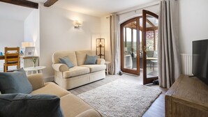 A cozy living room with a sofa, a coffee table, and a TV stand. - Manor Farm Barn Cottage - Close Lake District & Yorkshire Dales (Yealand Conyers)