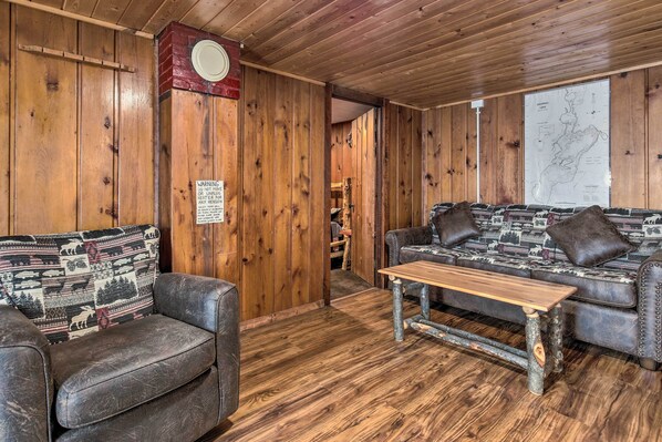 A wooden cabin interior with a sofa, a wooden table, and a map on the wall. - Lakefront Minocqua Cabin w/ Dock, Wifi & AC (Minocqua)