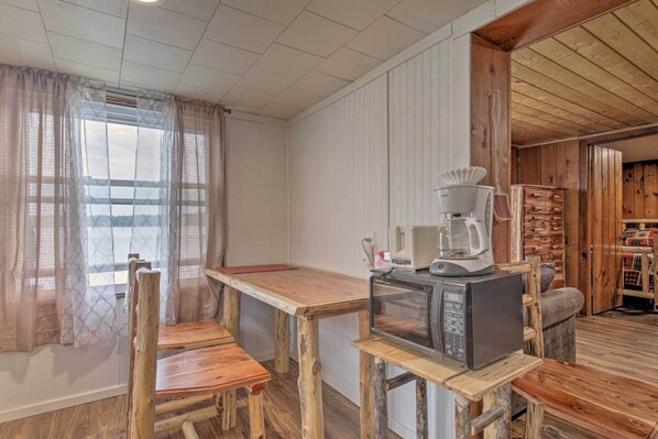 A rustic wooden interior with a wooden table and chairs, a microwave, and a coffee maker. - Lakefront Minocqua Cabin w/ Dock, Wifi & AC (Minocqua)