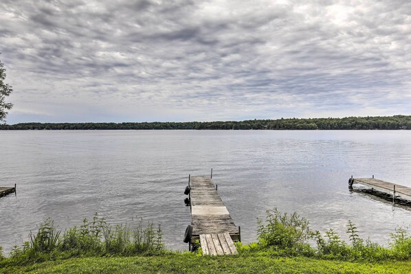 A wooden dock extending into calm water with a forested shoreline in the background. - Lakefront Minocqua Cabin w/ Dock & Fire Pit! (Minocqua)